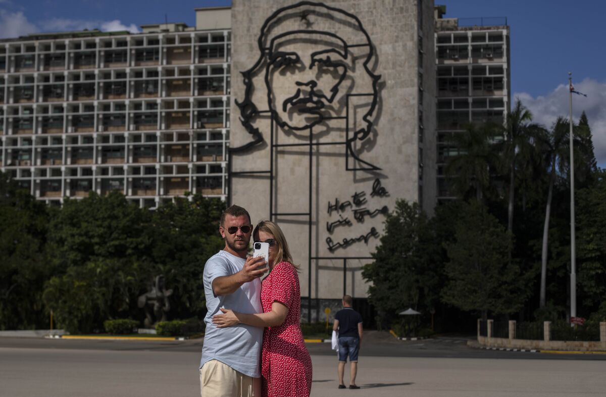 A couple of Russian tourists take a selfie in front of an image of Cuban revolutionary icon, Ernesto "Che" Guevara, at Revolution Plaza in Havana, Cuba, Monday, Nov. 8, 2021. Cuba is preparing to reopen to the world on Nov. 15, following lockdown restrictions. (AP Photo / Ramon Espinosa)