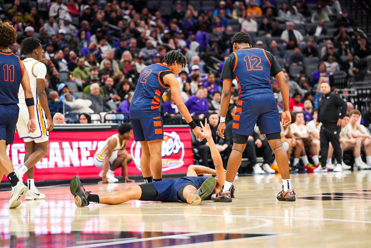 Roosevelt's Brayden Burries is helped up by Myles Walker after making a three-pointer while being fouled.