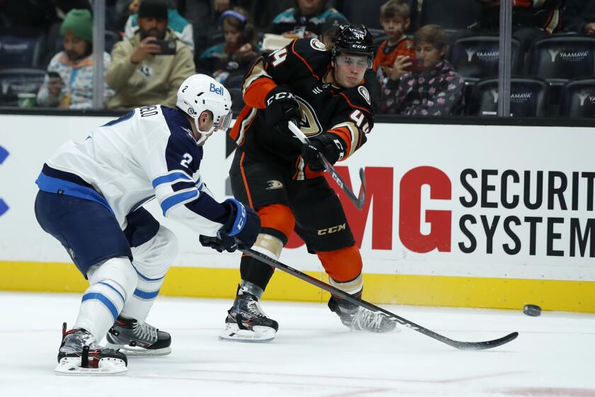 Anaheim Ducks left wing Max Comtois, right, takes a shot against Winnipeg Jets defenseman Dylan DeMelo, left, during the second period of an NHL hockey game in Anaheim, Calif., Tuesday, Oct. 26, 2021. (AP Photo/Alex Gallardo)