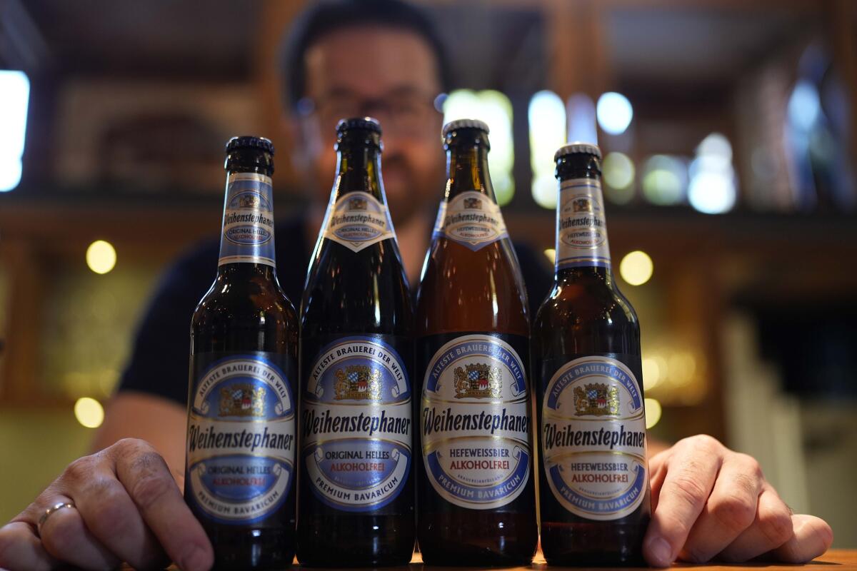 Brewmaster Tobias Zollo stands behind a row of four beer bottles