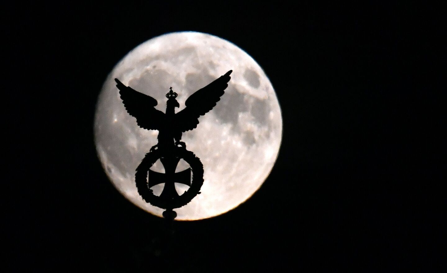 The moon is seen behind the Prussian eagle on top of the Brandenburg Gate in Berlin.