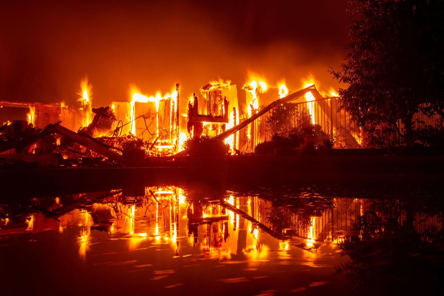 A burning home is reflected in a pool during the Carr fire in Redding on July 27.