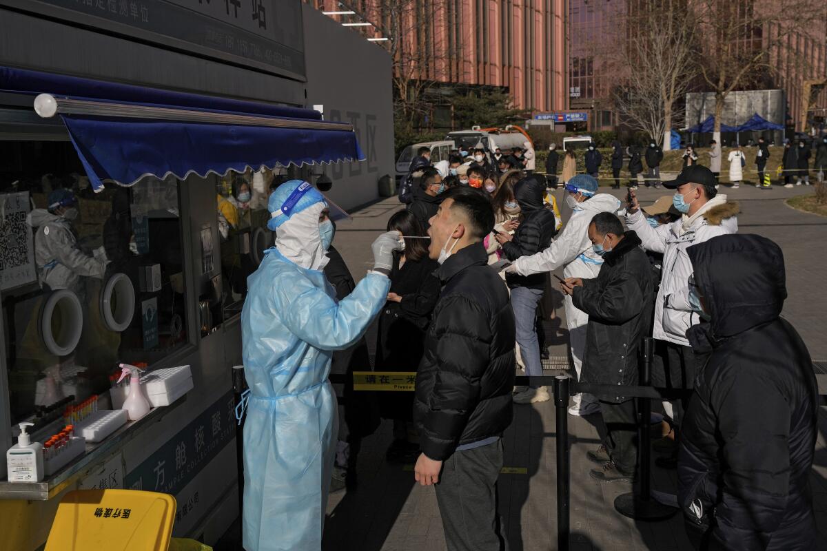 People line up to get a nasal swab for the COVID-19 test to meet traveling requirements at a mobile coronavirus testing facility outside a commercial office buildings in Beijing, Sunday, Jan. 16, 2022. Beijing has reported its first local omicron infection, according to state media, weeks before the Winter Olympic Games are due to start. (AP Photo/Andy Wong)