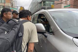 Wang Gang, de 36 años, delante, un migrante chino, habla con el conductor de un coche junto a otras personas mientras intentan conseguir un trabajo jornalero en la construcción o en otro oficio en el barrio de Flushing, en el barrio neoyorquino de Queens, el 3 de mayo de 2024. (AP Foto/Fu Ting)