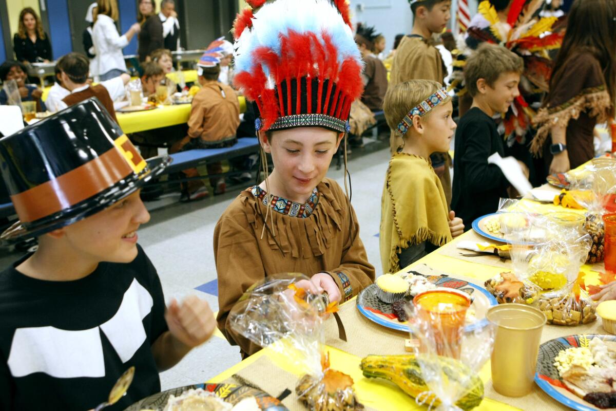 Matthew Plocher, dressed as a pilgrim, left, and Jensen Karlich, dressed as a Native American, right, enjoy the annual fifth grade Thanksgiving lunch at La Cañada Elementary in La Cañada Flintridge on Friday, Nov. 18, 2016.