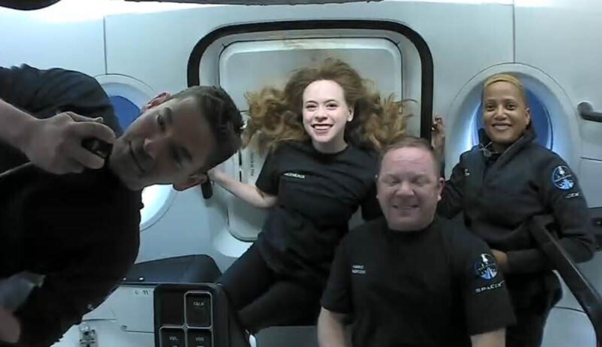 Two men and two women pose for a photograph while in orbit.