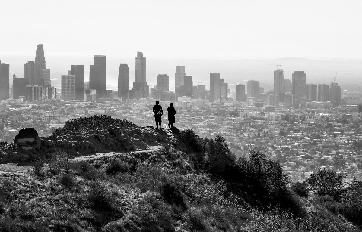 Two people at Griffith Park gaze at the view of downtown Los Angeles