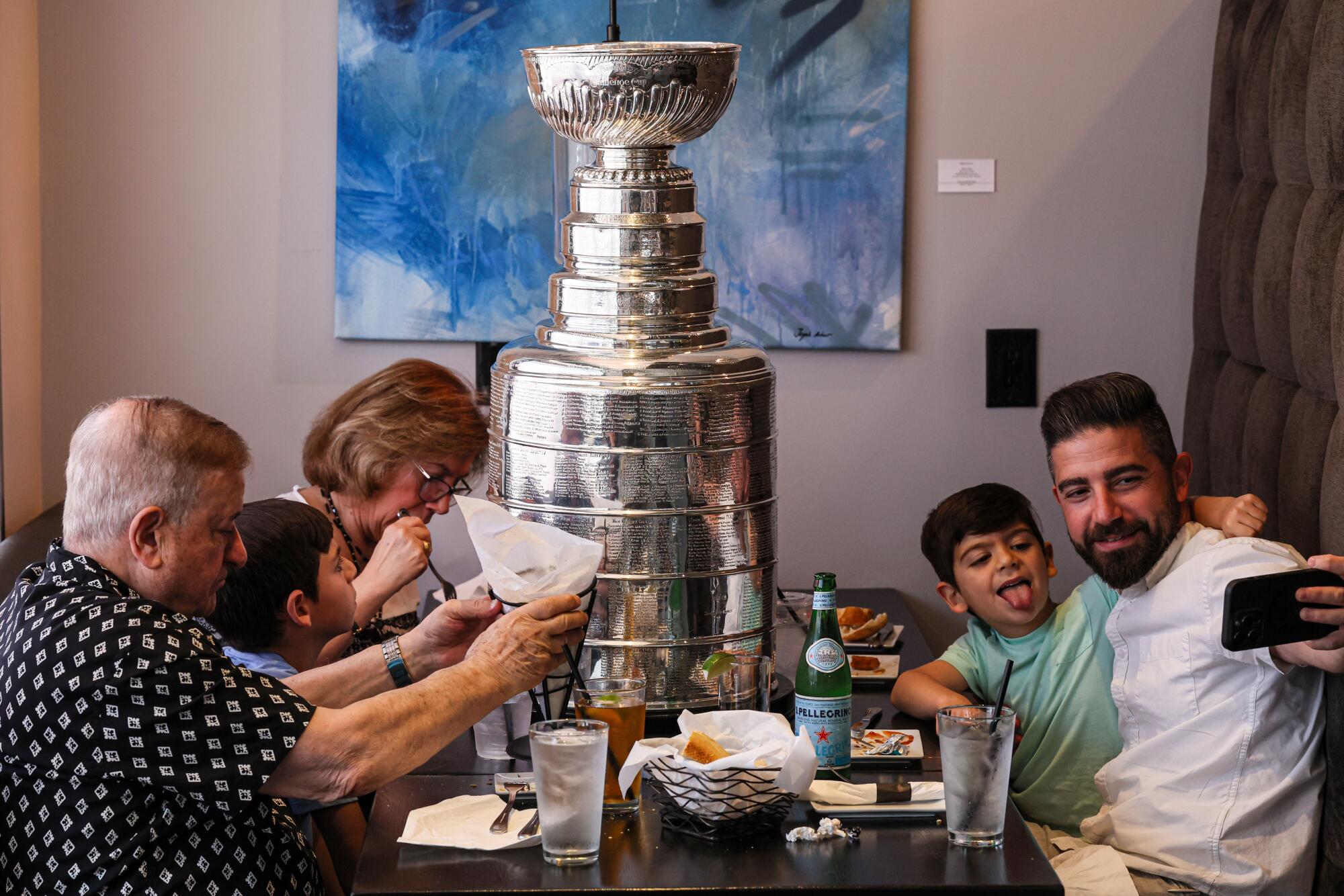 Nareg Dekermenjian uses his mobile phone to take a photo of himself and his son, Oliver, and the Stanley Cup.