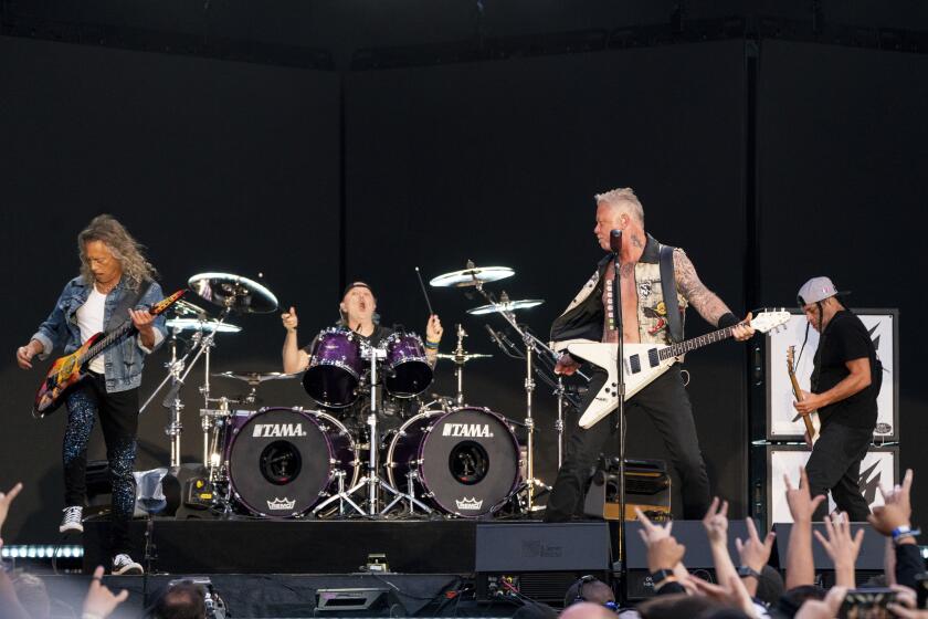 Three men with guitars and one drummer perform on stage. 