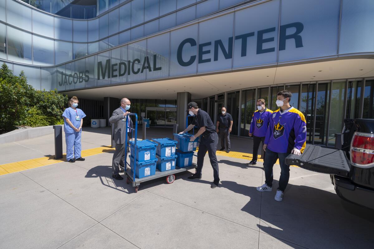 Brad Ouellet (left of cart), director of Supply Chain Management Services at UC San Diego Health, Steve Govett, president of the San Diego Seals lacrosse team (right of cart), UC San Diego Health nurses and Seals players handle a delivery of personal protective equipment.