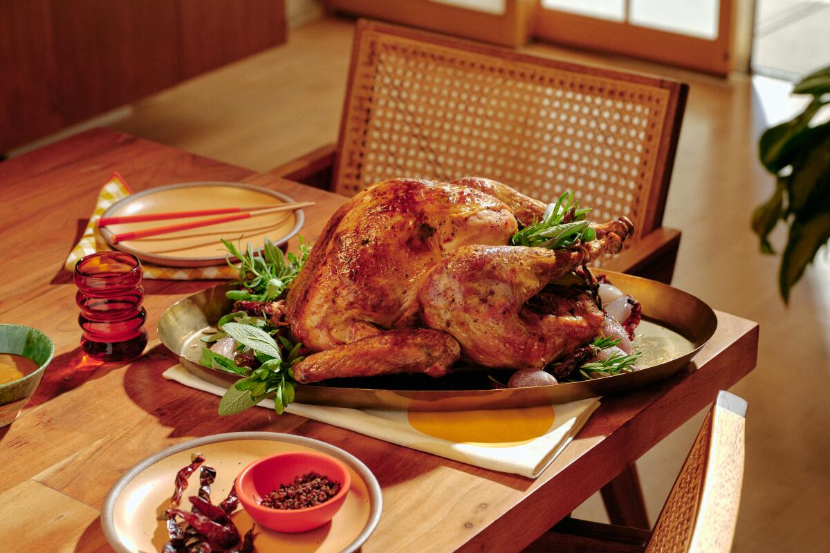 A roasted turkey sits on a platter on a wooden table