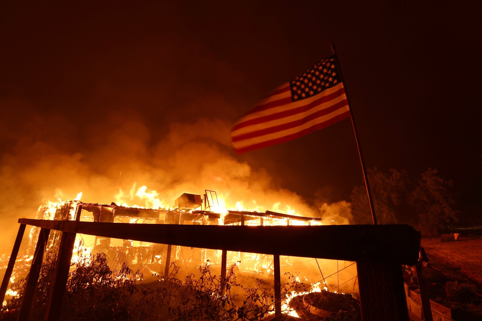 A home burns as American flag is seen.