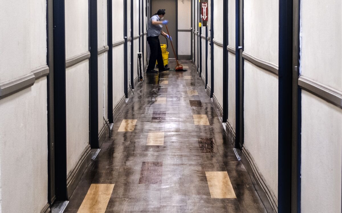 A person mops the hall way inside the SRO "Madison Hotel" on Friday, Dec. 9, 2022, in Los Angeles