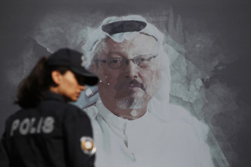 A Turkish police officer walks past a picture of slain Saudi journalist Jamal Khashoggi prior to a ceremony, near the Saudi Arabia consulate in Istanbul, marking the one-year anniversary of his death, Wednesday, Oct. 2, 2019. A vigil was held outside the consulate building Wednesday, starting at 1:14 p.m. (1014 GMT) marking the time Khashoggi walked into the building. (AP Photo/Lefteris Pitarakis)