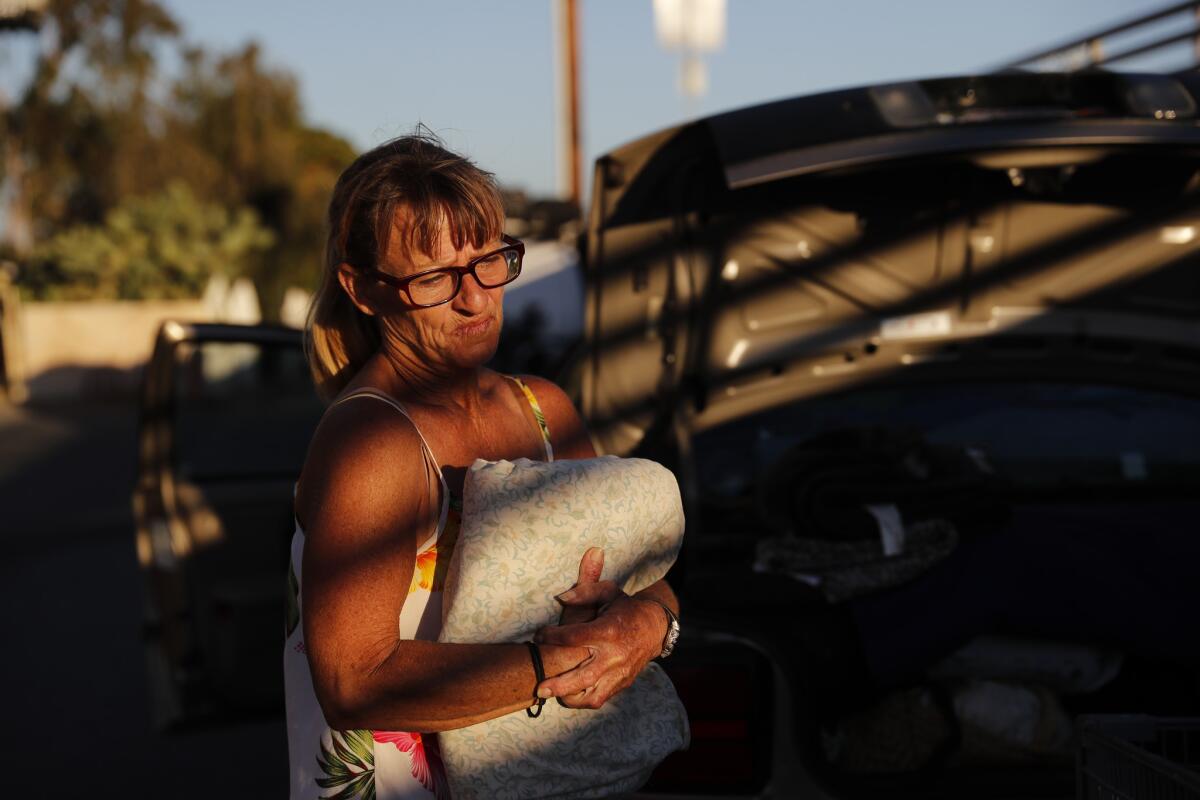 Lisa Weber, 57, who has been homeless on-and-off for 30 years, packs all of her belongings into her car across the street from her encampment along the Santa Ana River trail.