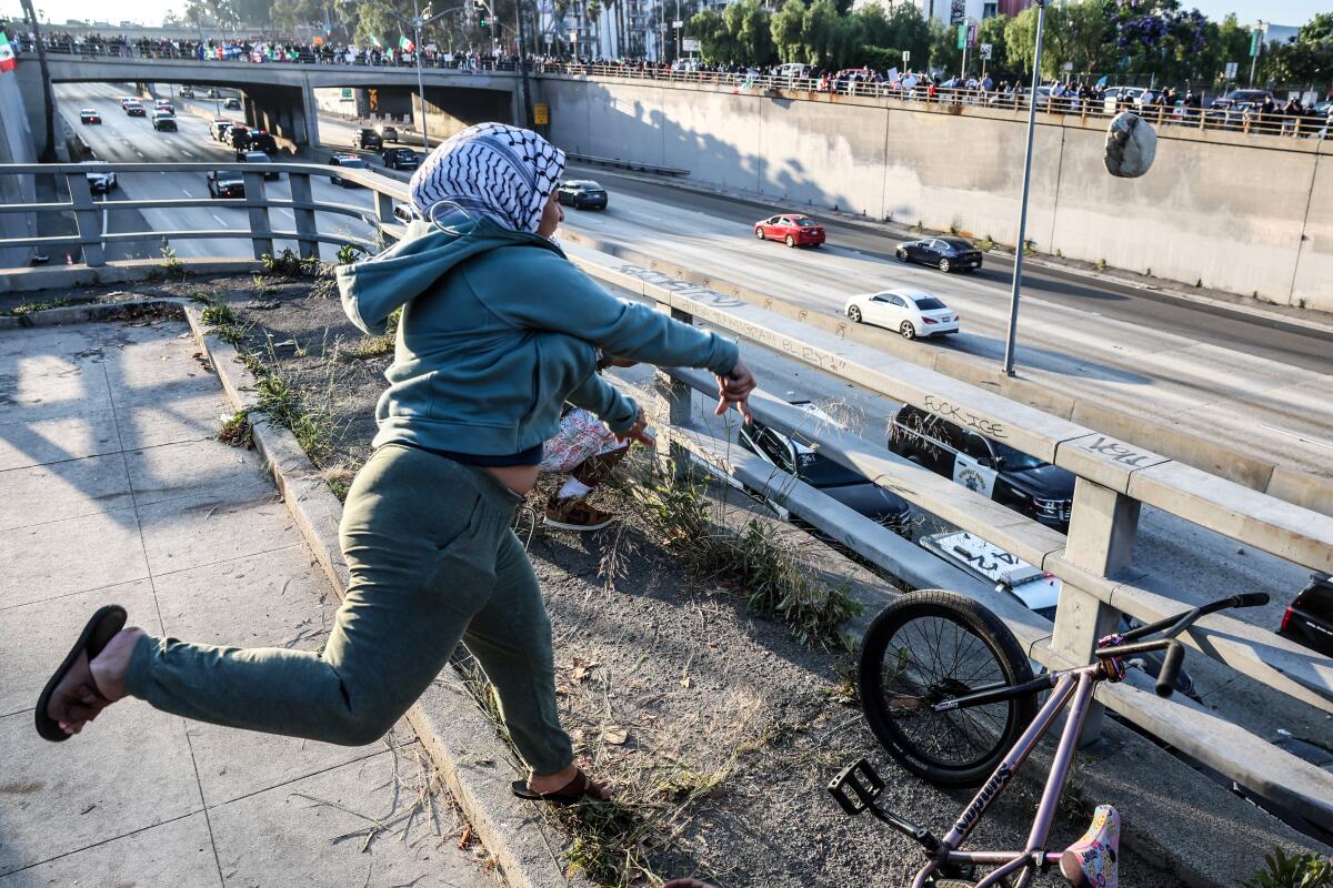 A protester lobs a large rock at CHP officers.