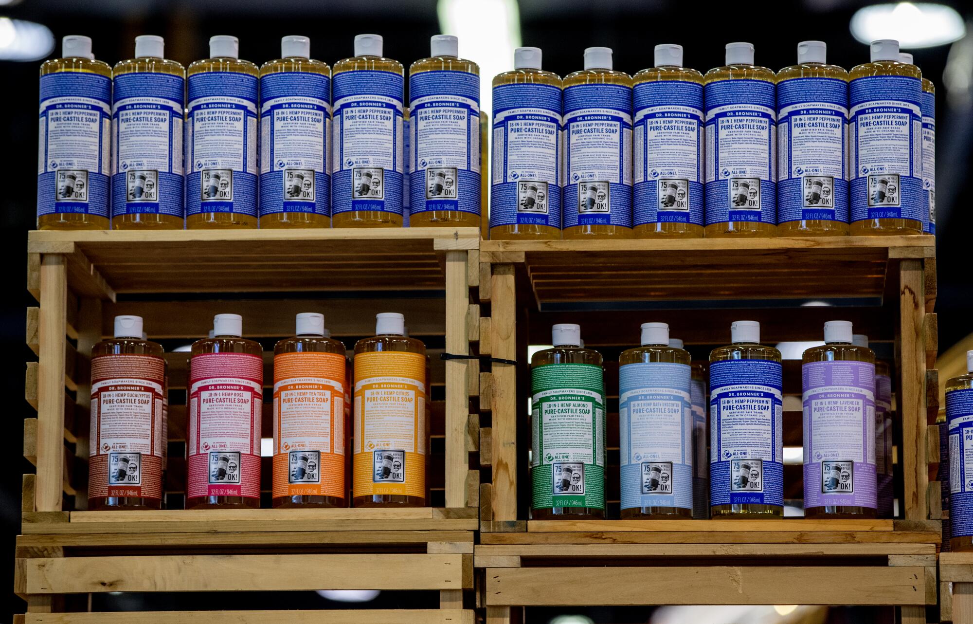 Bottles of liquid soap in multiple colors lined up on rugged shelves