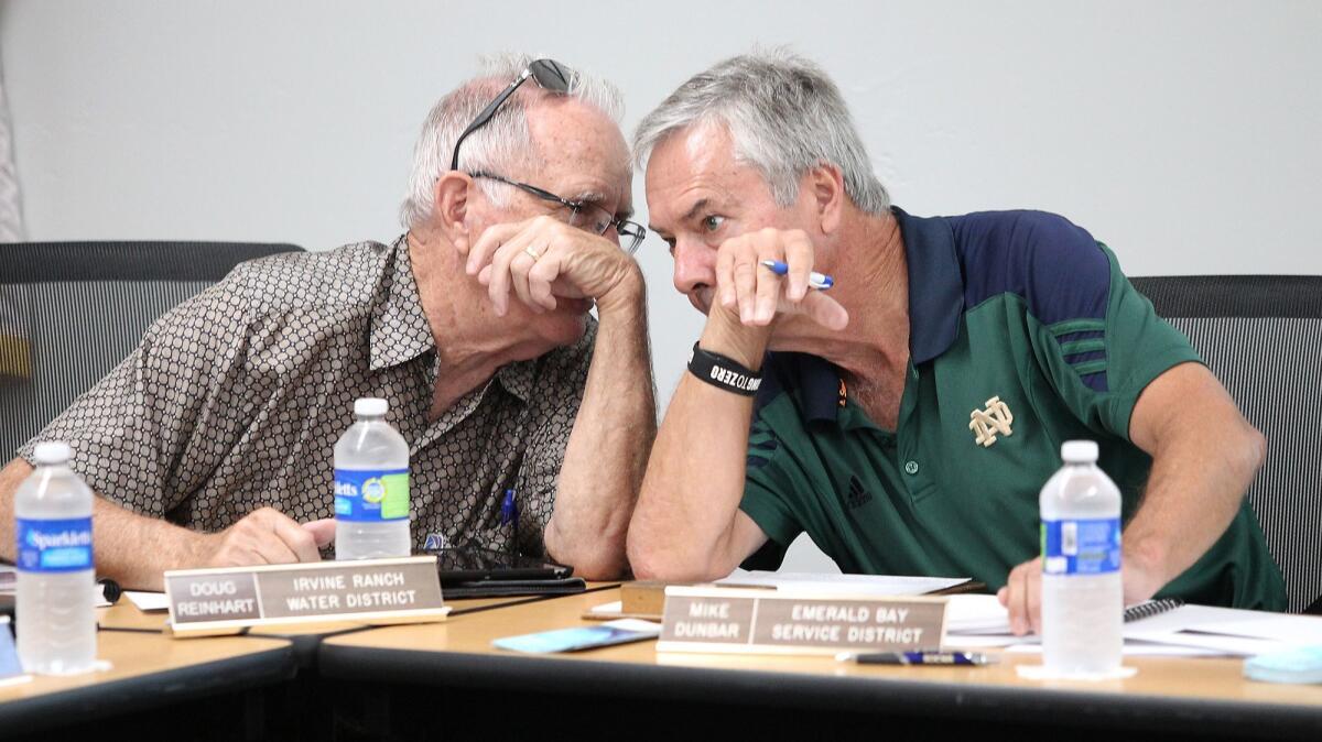 Doug Reinhart, Irvine Ranch Water District board president, left, and Mike Dunbar, Emerald Bay Service District general manager, chat before Thursday's South Orange County Wastewater Authority board meeting.