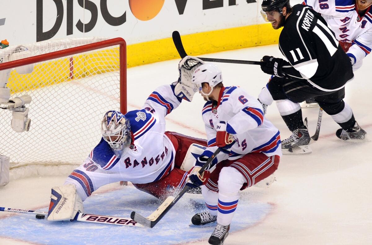 New York Rangers goalie Henrik Lundqvist makes a save on a shot by Kings center Anze Kopitar, top right, as Rangers defenseman Anton Stralman looks on during the third period of the Kings' 3-2 overtime win in Game 1 of the Stanley Cup Final.