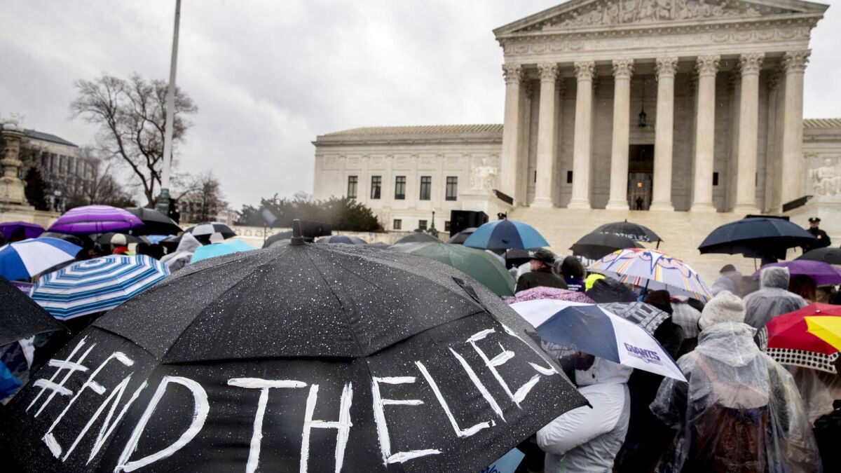 Abortion-rights supporters hold an umbrella that reads "#EndTheLies" outside the Supreme Court building on March 20 as the court hears arguments in a case concerning California's attempt to regulate antiabortion crisis pregnancy centers.