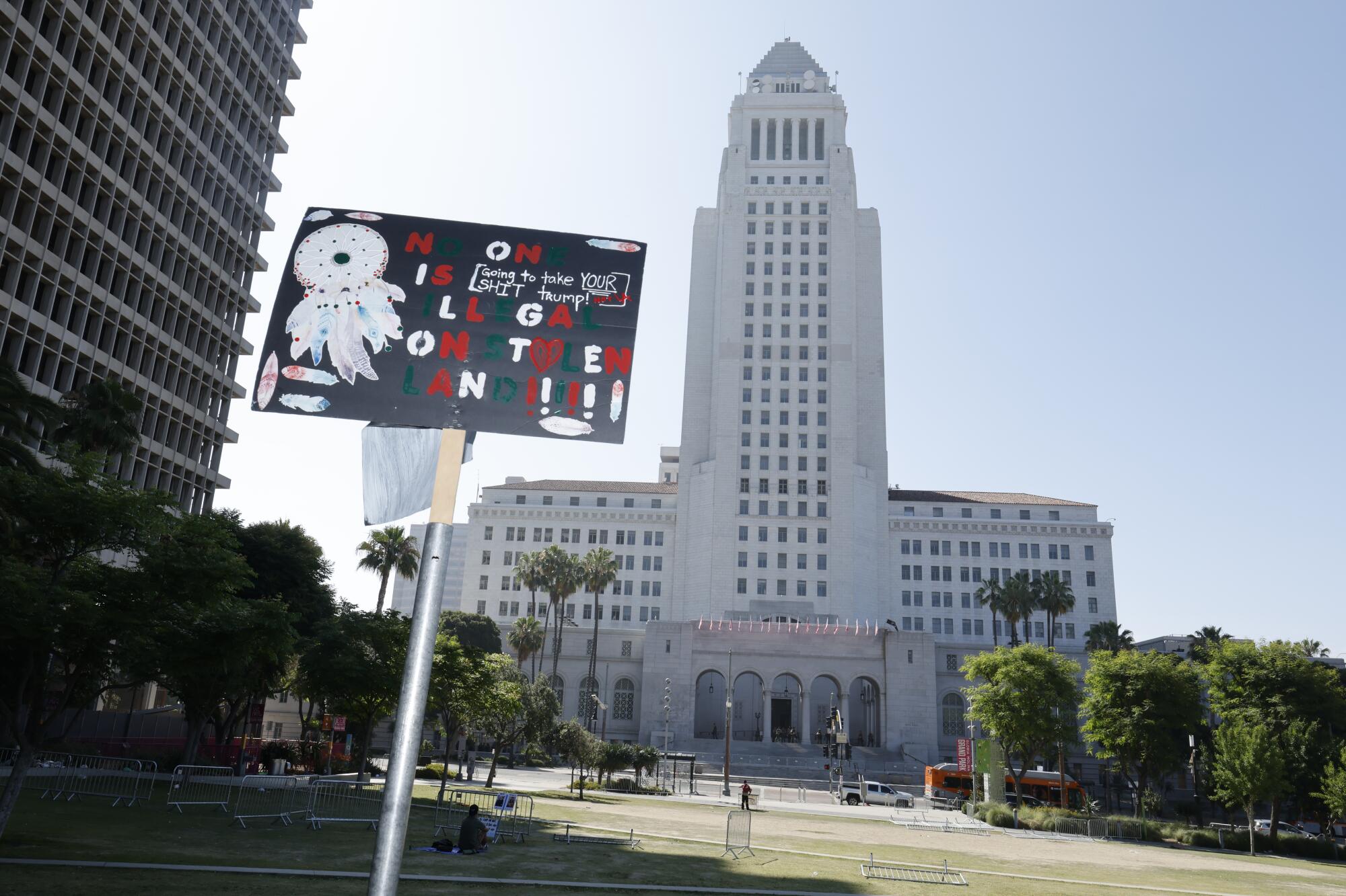 A protest sign rises before Los Angeles City Hall.