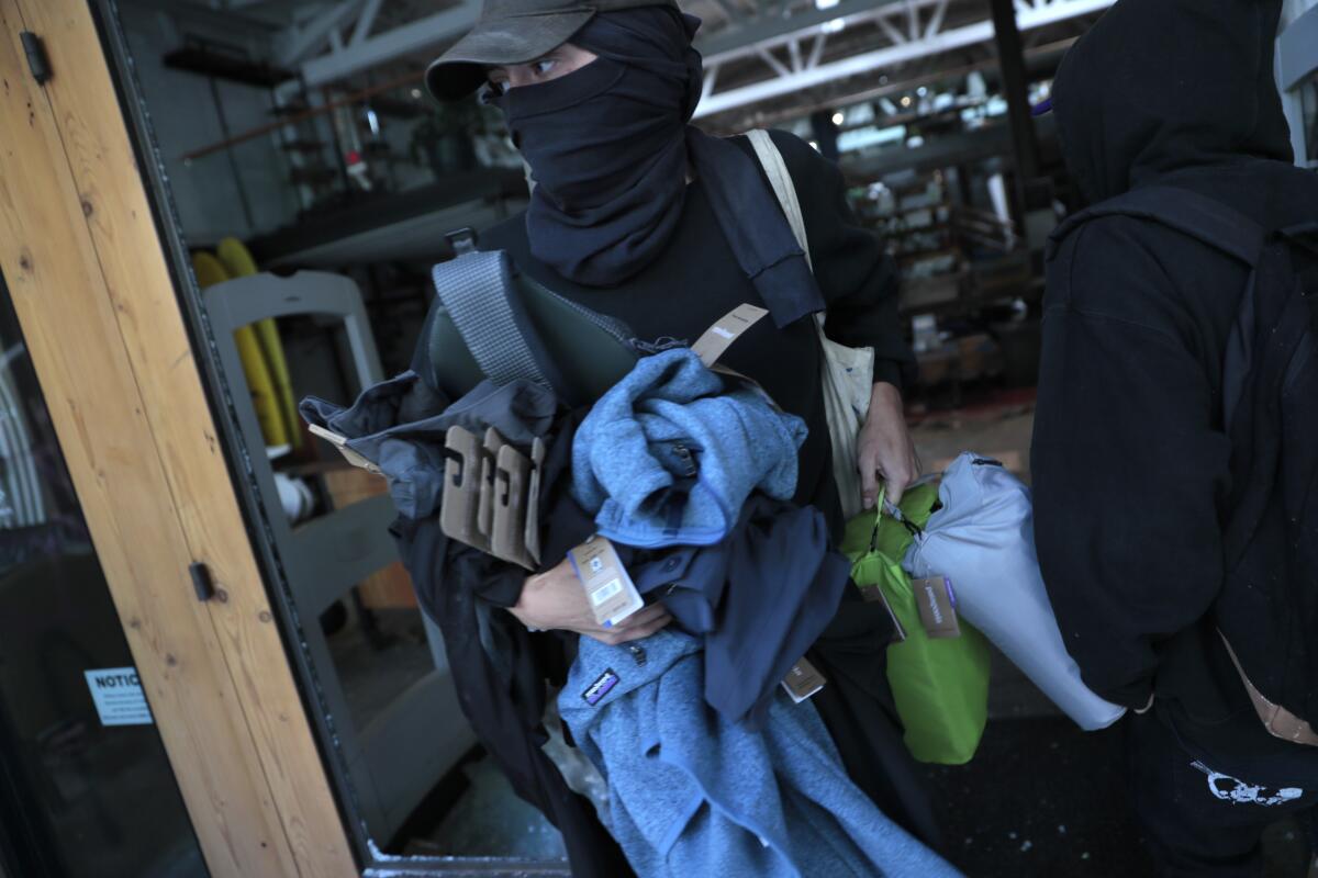 Looters rush out of the Patagonia Store on 4th St. in Los Angeles.