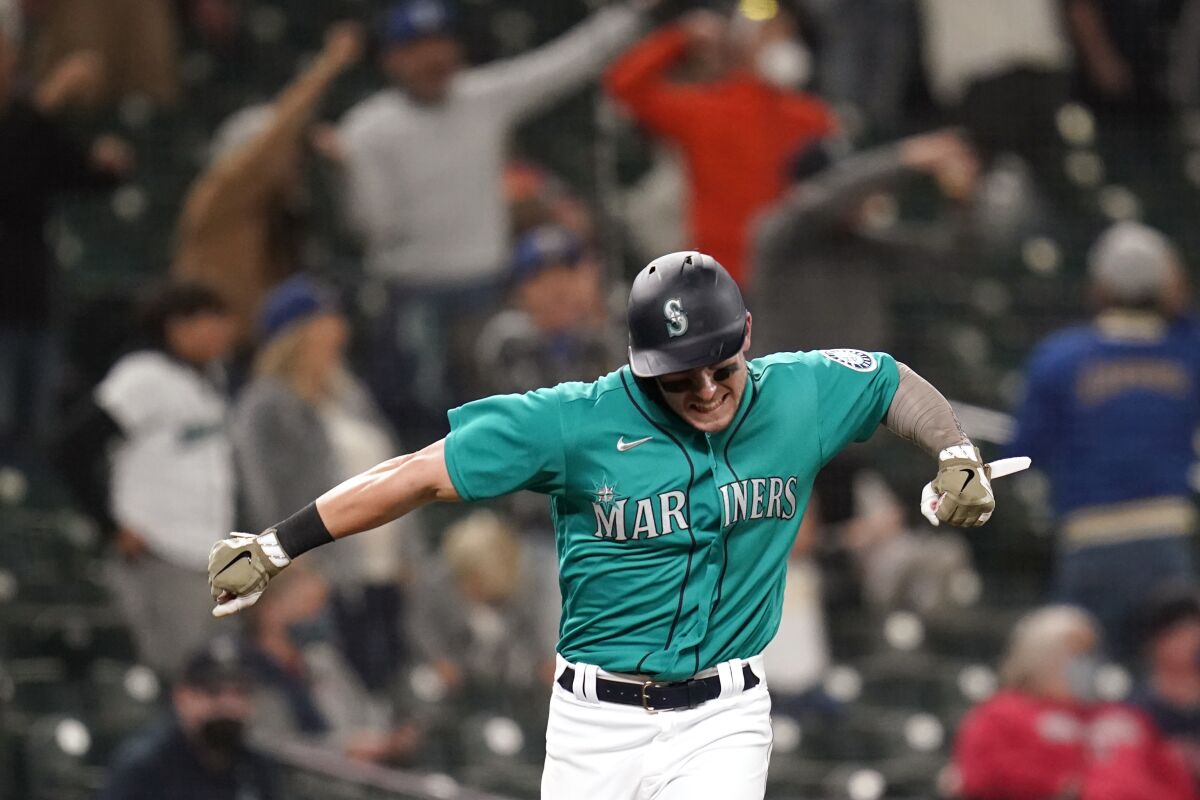 Seattle Mariners' Jarred Kelenic reacts to the home run of Mitch Haniger as he heads in to score against the Cleveland Indians during the seventh inning of a baseball game Friday, May 14, 2021, in Seattle. (AP Photo/Elaine Thompson)