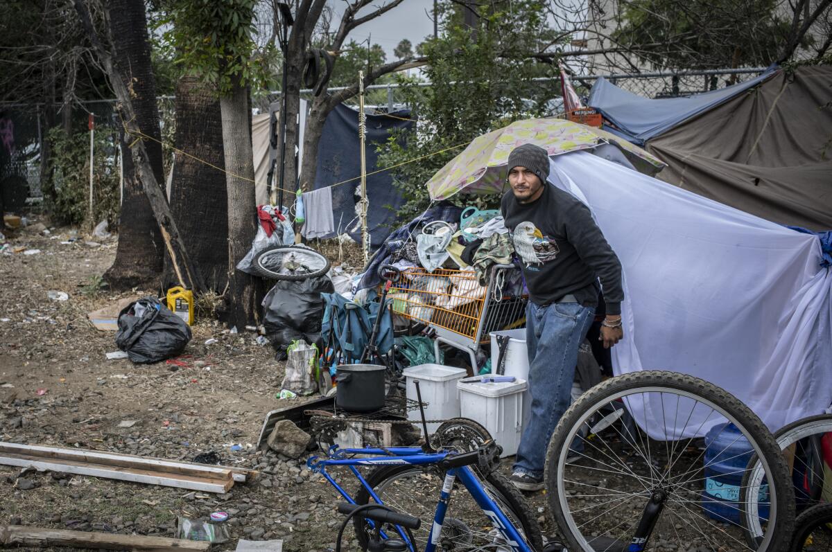 Jose Duran emerges from his shelter at a homeless encampment near train tracks in Northridge.