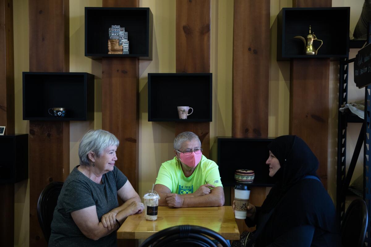 Three people chat over coffee