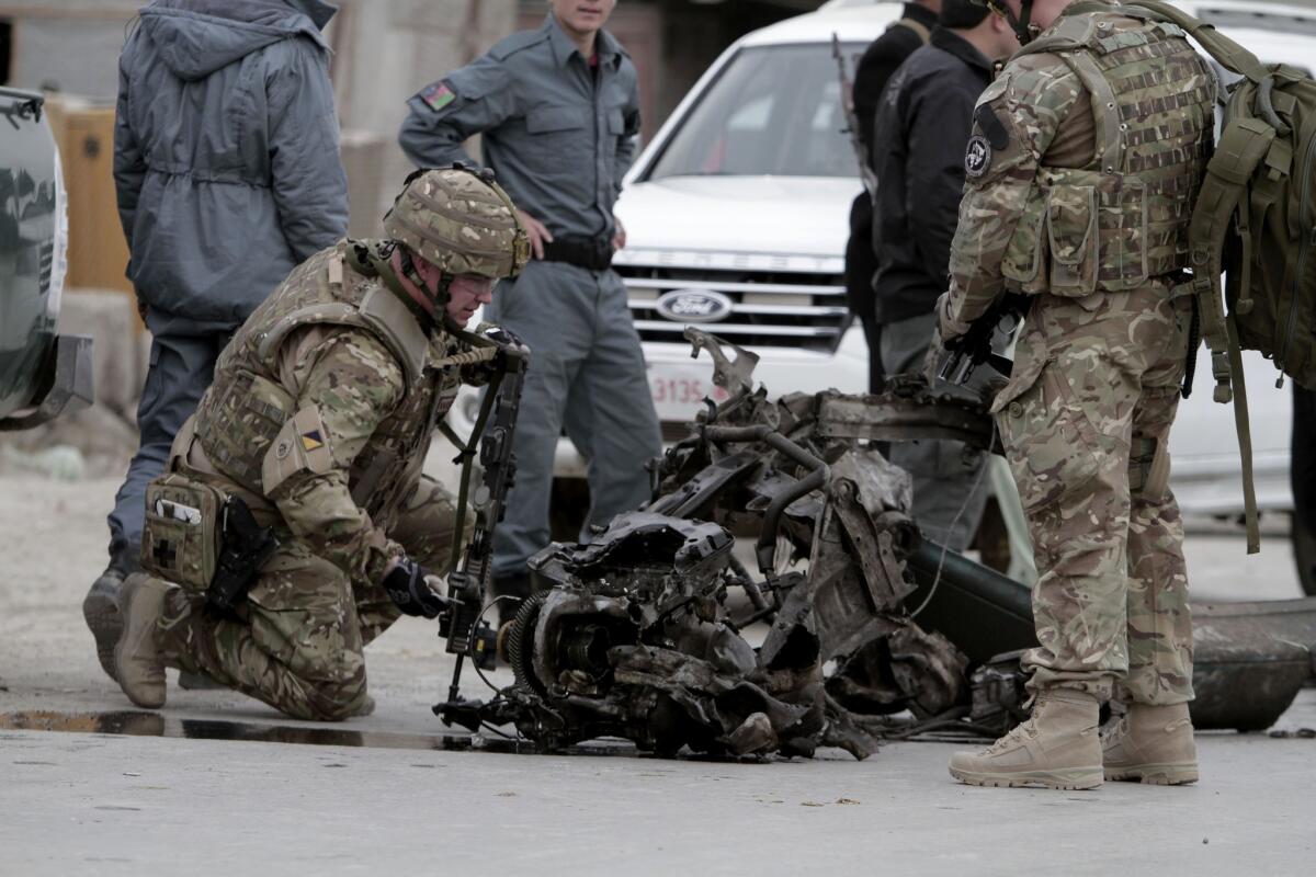 NATO troops examine the remains of a car after a suicide bomb attack in Kabul that killed three coalition members.