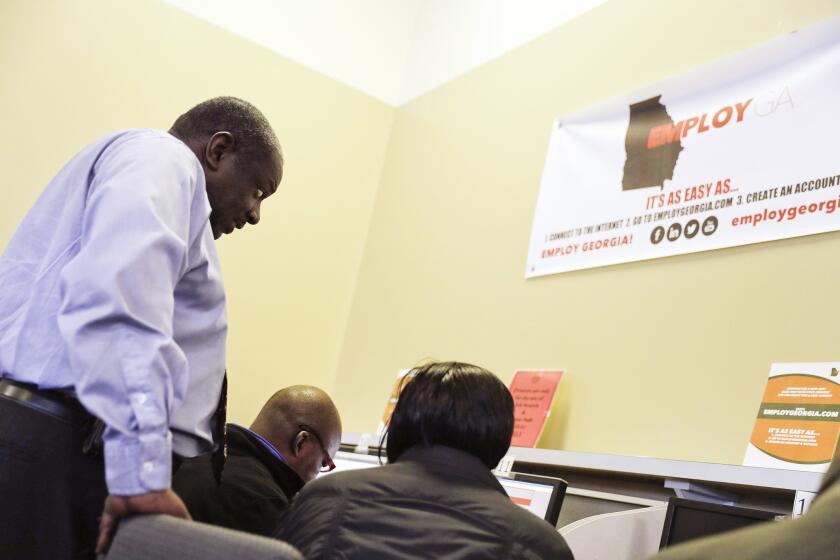 Georgia Department of Labor services specialist Eric Frasier, left, helps a woman with a job search at an unemployment office in Atlanta on March 3.