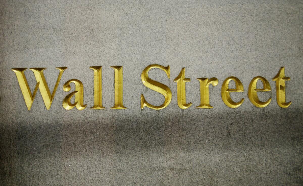 In this Oct. 8, 2014, file photo, a Wall Street address is carved in the side of a building in New York.
