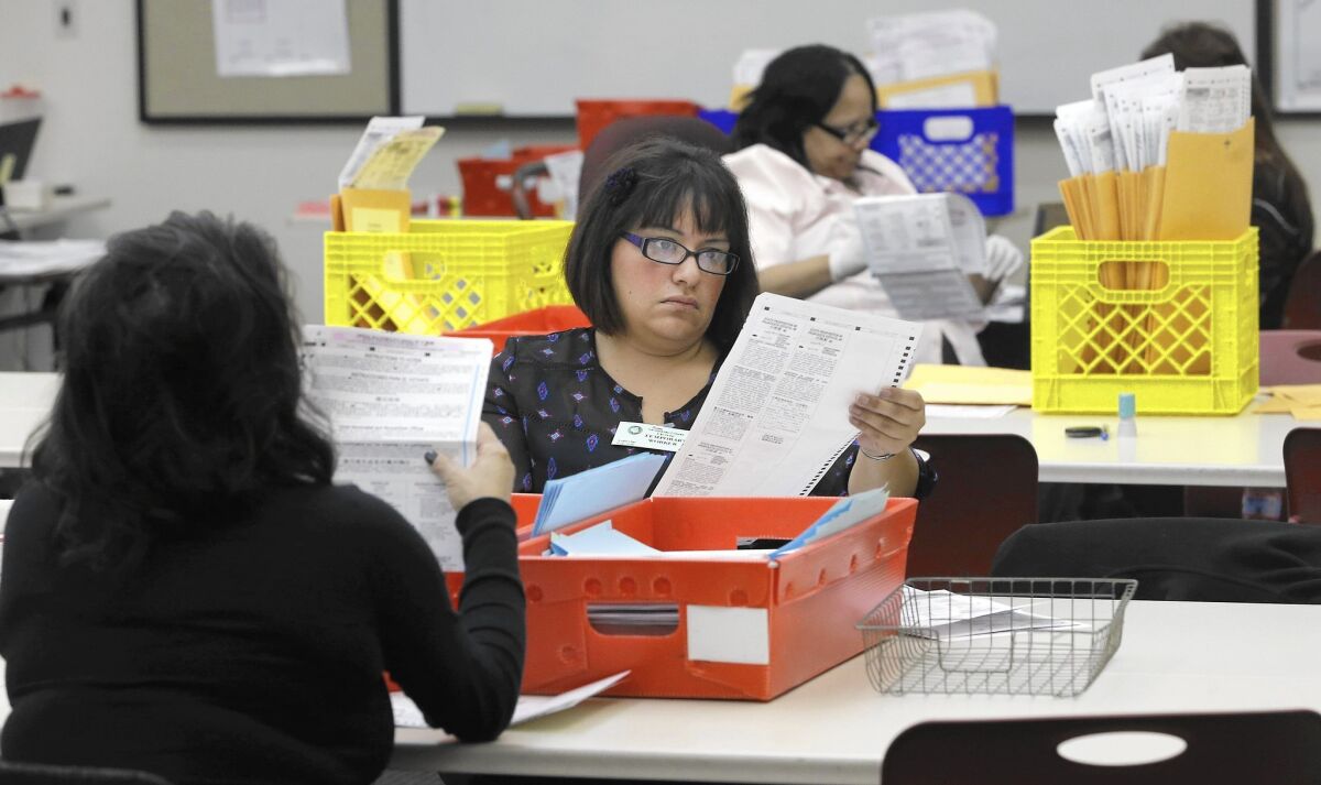 Lydia Harris, a temporary worker at the Sacramento Registrar of Voters, looks over a mail-in ballot before it is sent to be counted a week after polls closed in the 2014 election. (Rich Pedroncelli / Associated Press)
