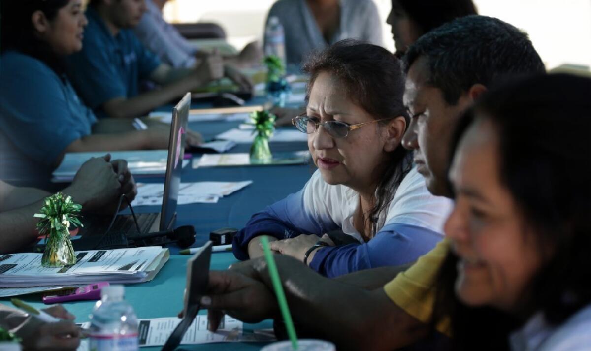 L.A. consumers may see modest increases next year on their health coverage under the Affordable Care Act. Above, families sign up at an L.A. enrollment event in April.