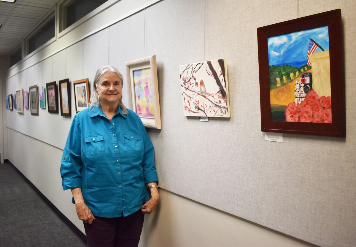 Artist Betty Rexford with her paintings on display in the Rancho Bernardo Library.