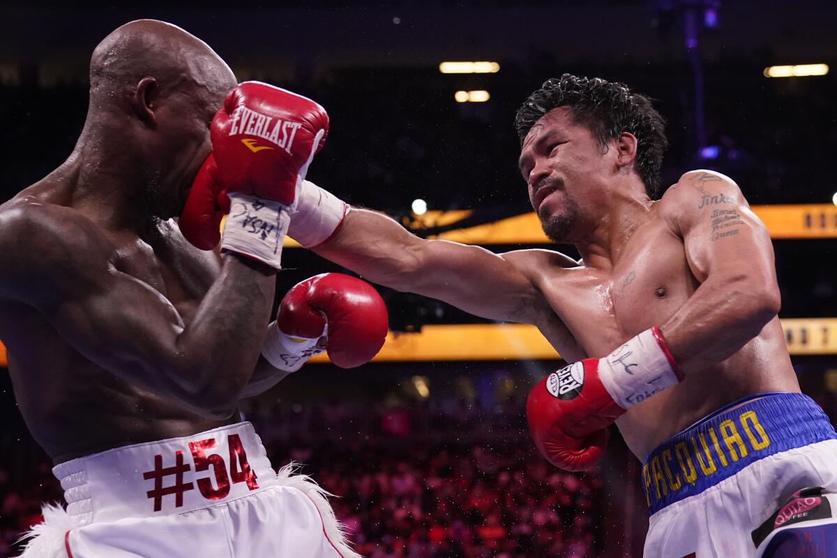 Manny Pacquiao, right, of the Philippines, hits Yordenis Ugas, of Cuba