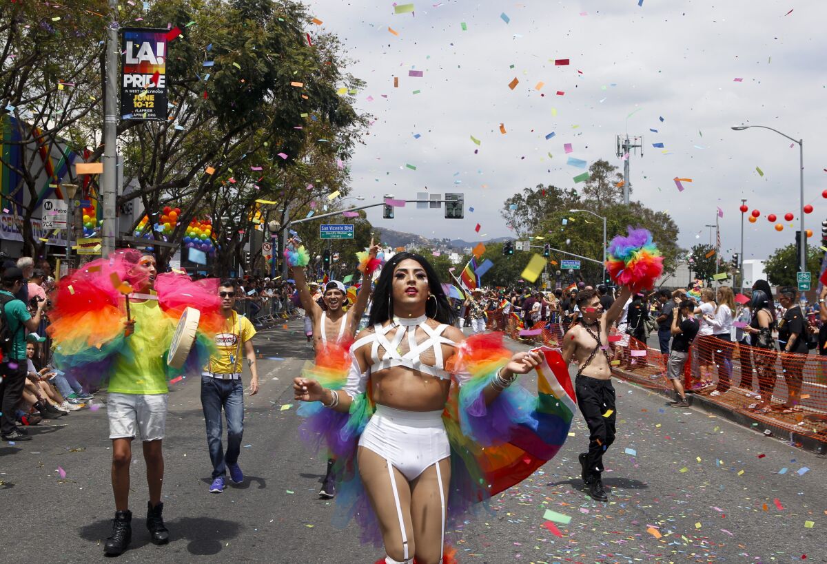 A drag queen leads a group in the LA Pride parade as rainbow confetti flies