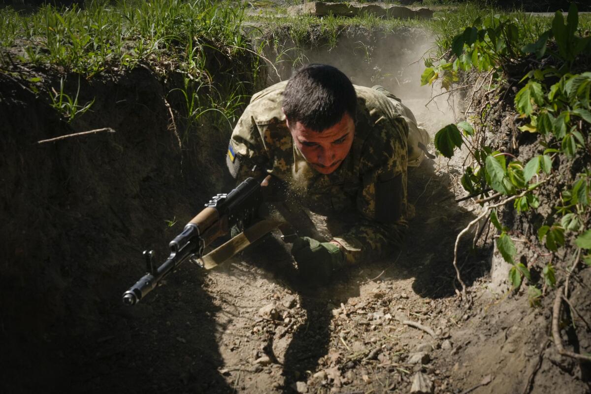 A soldier lies on the ground, holding a weapon.