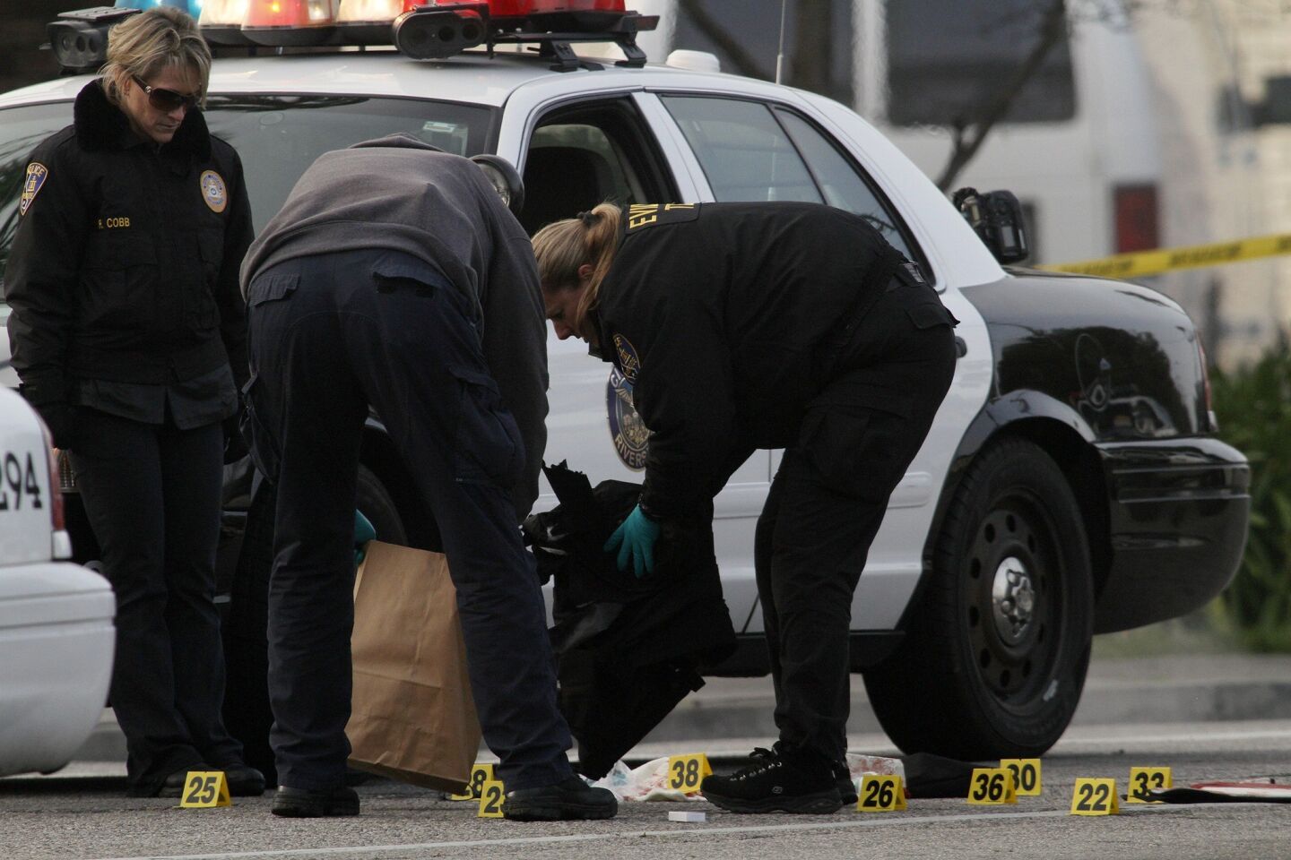 Riverside police investigators tag and bag evidence at the scene where two fellow officers were shot early Thursday. One was killed and the other was in critical condition.
