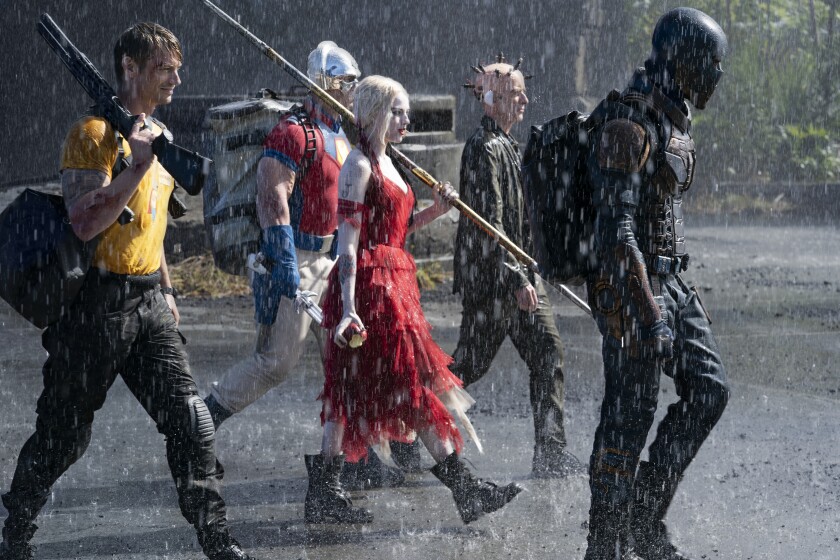 “The Suicide Squad” walks in the rain carrying weapons.