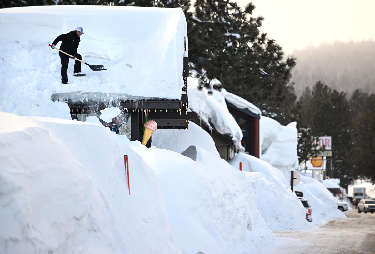 Brang Miller, owner of Mammoth Fun Shop, shovels snow off the roof of his store in Mammoth Lakes. 