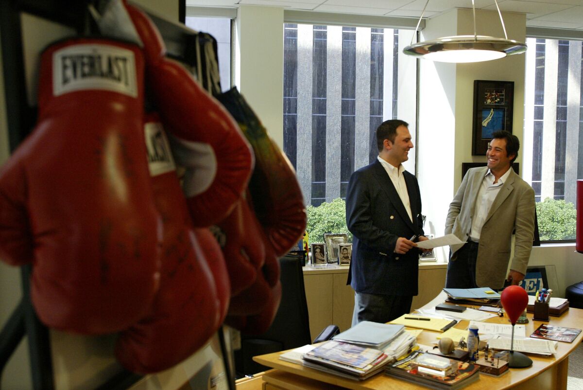 Former CEO of Golden Boy Promotions Richard Schaefer talks with Golden Boy founder and former boxer Oscar De La Hoya in 2005.
