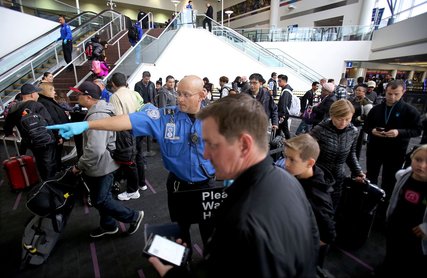 A TSA agent guides holiday travelers through a security checkpoint in Terminal 2 at LAX on Thursday, one of the busiest travel days of the year.
