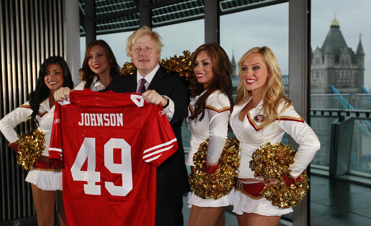 FILE - Boris Johnson, then Mayor of London center, and four of the 49ers cheerleaders Deanna Ortega, left, Morgan McLeod, Alexis Kofoed and Lauren Riccaboni, right, pose for the media as the Mayor holds a team shirt with his name on at City Hall in London Tuesday, Oct., 26, 2010. British media say Prime Minister Boris Johnson has agreed to resign on Thursday, July 7 2022, ending an unprecedented political crisis over his future. (AP Photo/Alastair Grant, File)