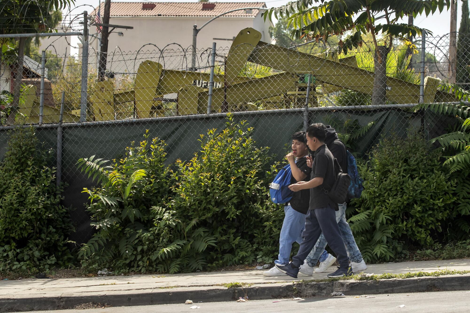 Three children walk past an urban oil field.