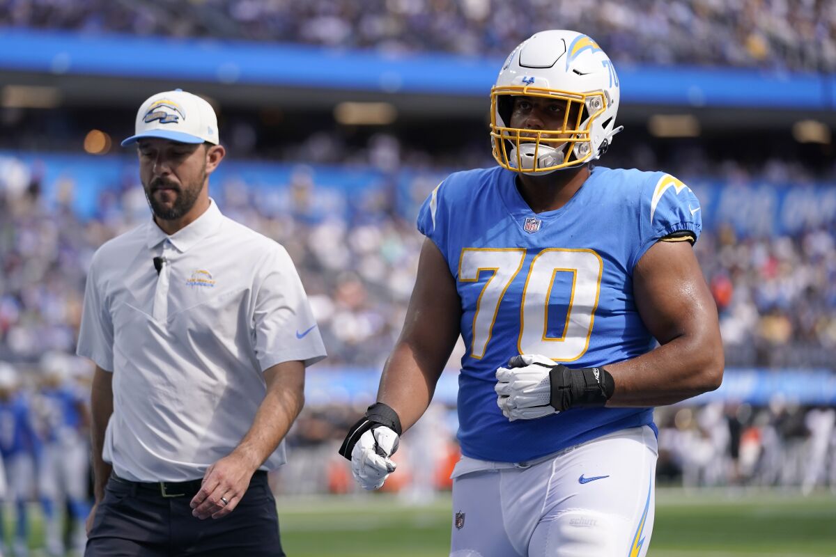 Chargers offensive tackle Rashawn Slater walks next to another man.
