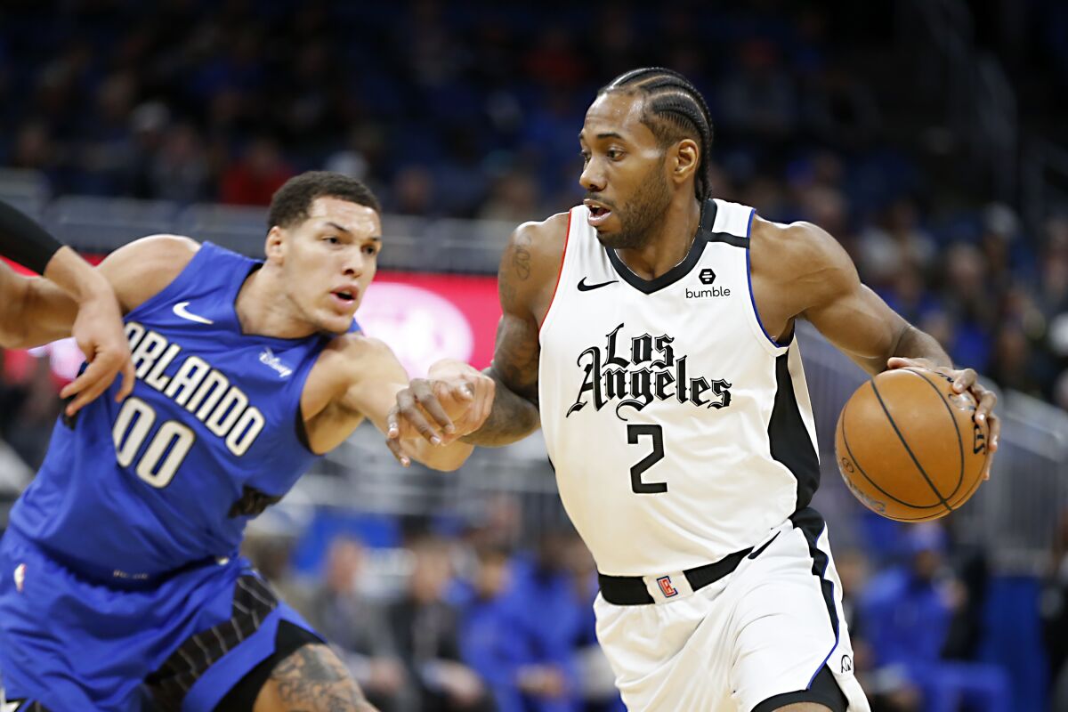 Los Angeles Clippers forward Kawhi Leonard (2) drives past Orlando Magic forward Aaron Gordon (00) during the first quarter of an NBA basketball game in Orlando, Fla. on Sunday.