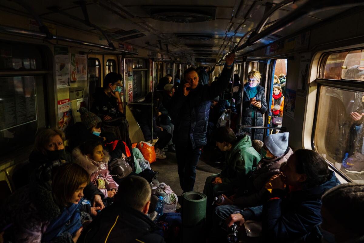 hundreds of people sit in a dark subway car with their belongings and pets