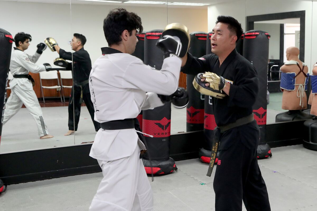 Master John Seock, right, trains Sage Hill School senior Aiden Kiani, left.