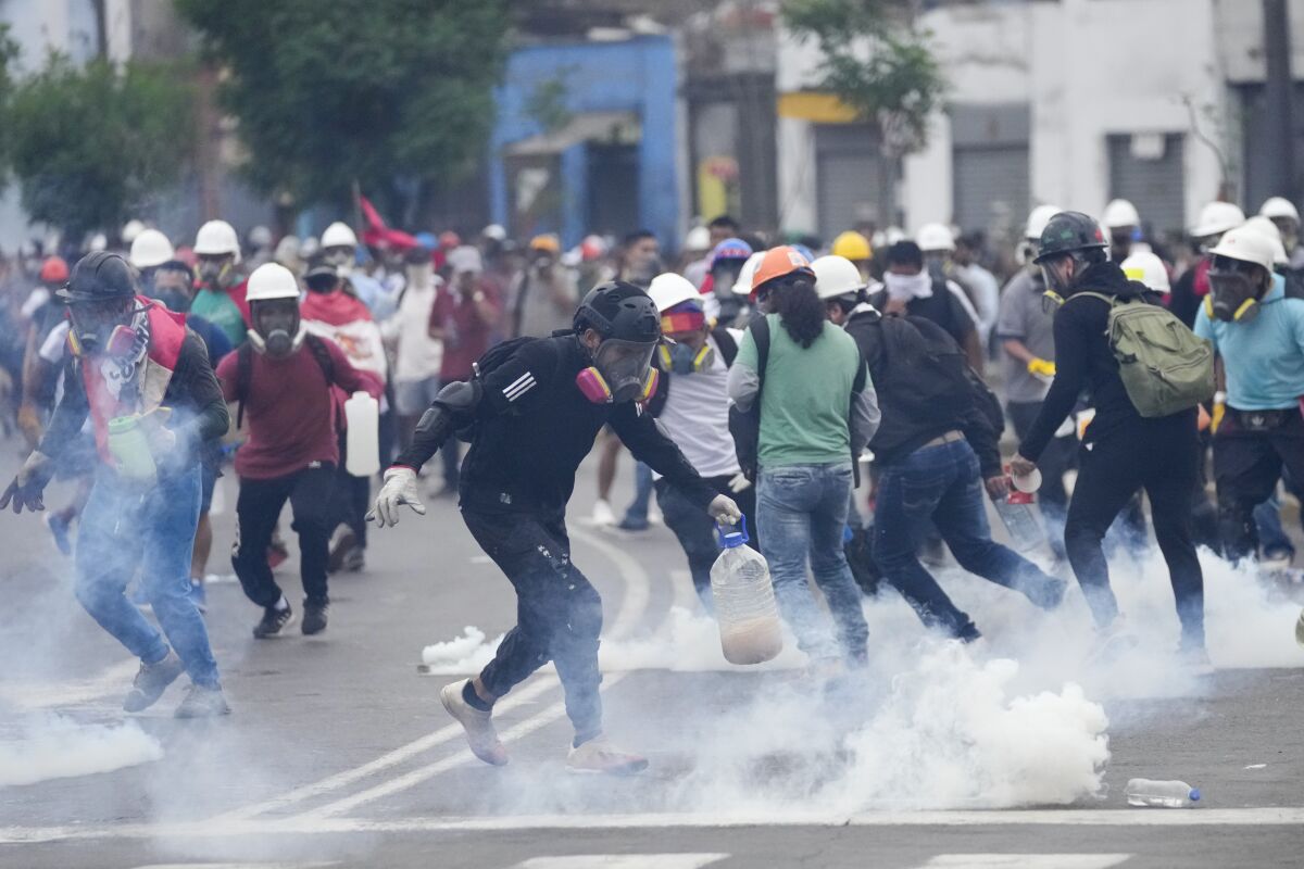 Varios manifestantes antigubernamentales recogen cartuchos de gas lacrimógeno que les lanzó la policía